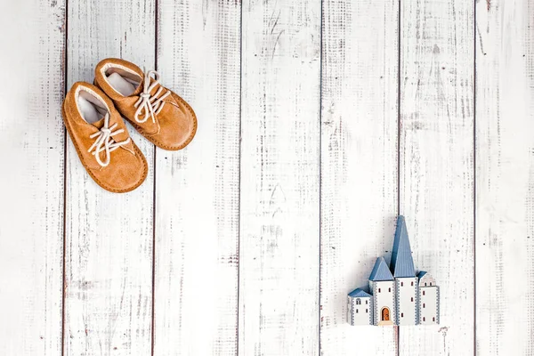 little kids retro shoes and a house made of blocks on a wooden background, eco style, childhood and parenthood concept