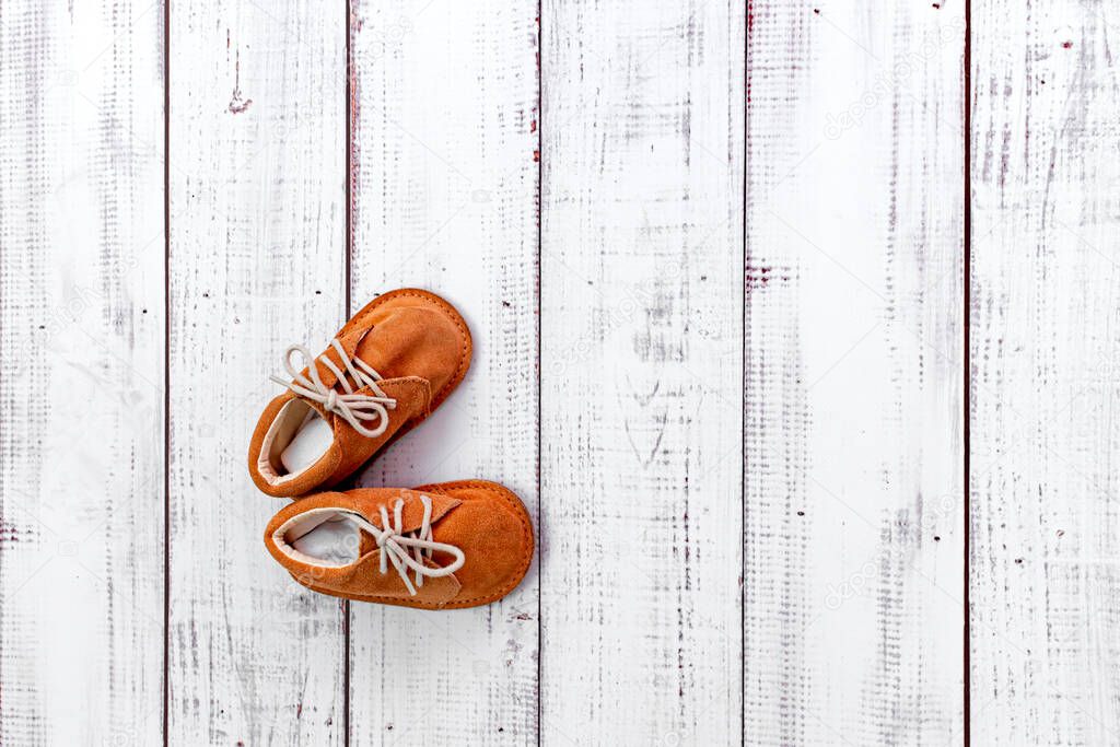 children's boots on a white wooden floor, the concept of comfort and warmth at home, baby's first steps