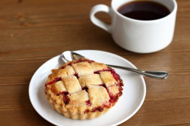 Ev kiraz pasta beyaz tabak ve bardak kahve americano ahşap masa üzerinde kafes ve metal kaşık ile yapılan 