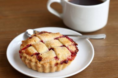 Ev kiraz pasta beyaz tabak ve bardak kahve americano ahşap masa üzerinde kafes ve metal kaşık ile yapılan 