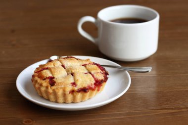 Ev kiraz pasta beyaz tabak ve bardak kahve americano ahşap masa üzerinde kafes ve metal kaşık ile yapılan 