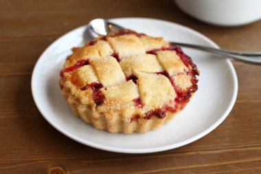 Ev kiraz pasta beyaz tabak ve bardak kahve americano ahşap masa üzerinde kafes ve metal kaşık ile yapılan 