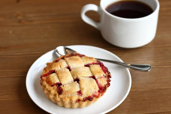 Ev kiraz pasta beyaz tabak ve bardak kahve americano ahşap masa üzerinde kafes ve metal kaşık ile yapılan 