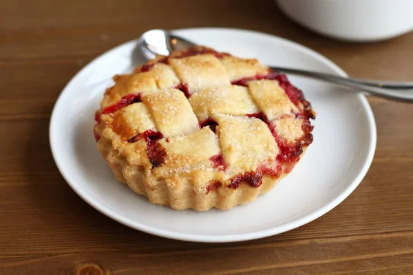 Ev kiraz pasta beyaz tabak ve bardak kahve americano ahşap masa üzerinde kafes ve metal kaşık ile yapılan 