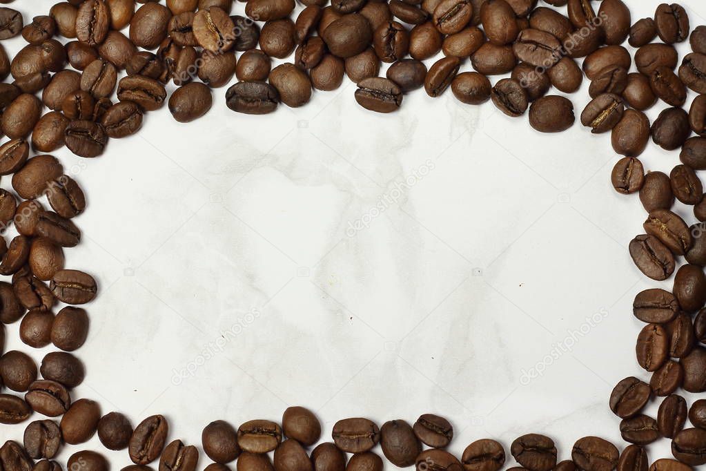 Frame of dark roasted coffee beans with marble texture copy space for text