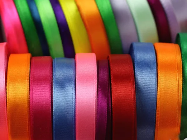 A lot of beautiful colored satin ribbons top view for decoration, gift wrapping and sewing in a fabric shop bright and colorful background close up