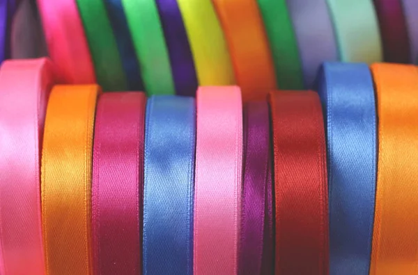 A lot of beautiful colored satin ribbons top view for decoration, gift wrapping and sewing in a fabric shop bright and colorful background close up