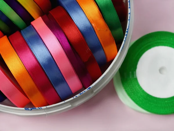 A lot of beautiful colored satin ribbons top view for decoration, gift wrapping and sewing in a fabric shop bright and colorful background close up