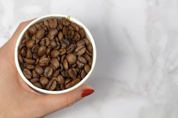 Kaffeebohnen Einem Pappbecher Weiblicher Hand Auf Einer Marmoroberflächenansicht Mit Kopierplatz — Stockfoto