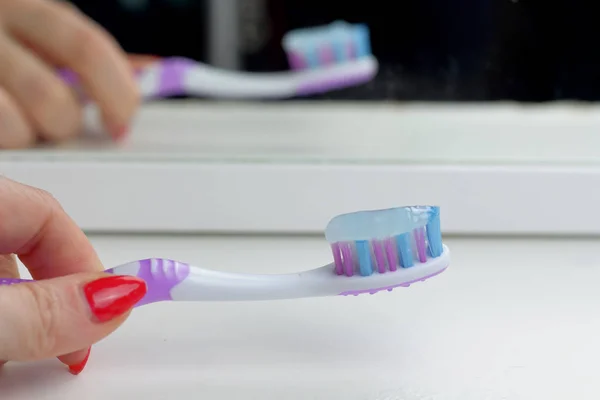 浴室白色架子上的粉红色牙刷反映在镜子里 早上护理 牙齿护理和健康在女性汉德 — 图库照片