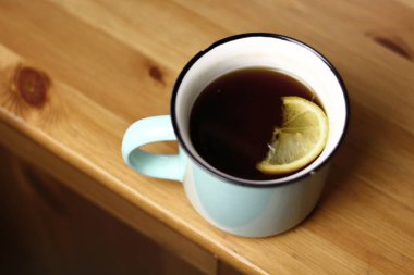 Ahşap doku ile bir tabloda bir ışık mavi kupa Limonlu sıcak ısınma çay