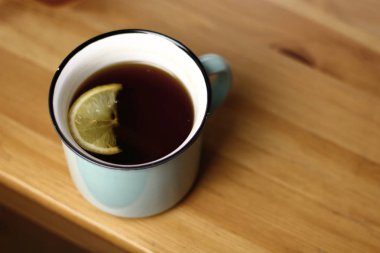 Ahşap doku ile bir tabloda bir ışık mavi kupa Limonlu sıcak ısınma çay