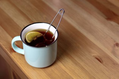 Sıcak çay demlendi çay süzgeci bir ahşap doku bir tablo ile bir ışık mavi kupa limon ile ısınma
