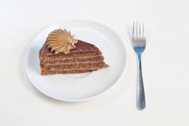 Bir parça çikolata kremalı dekorasyon tatlı çatal ile beyaz tabakta ile lezzetli çikolatalı kek