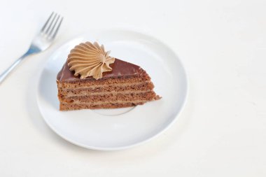 Bir parça çikolata kremalı dekorasyon tatlı çatal ile beyaz tabakta ile lezzetli çikolatalı kek