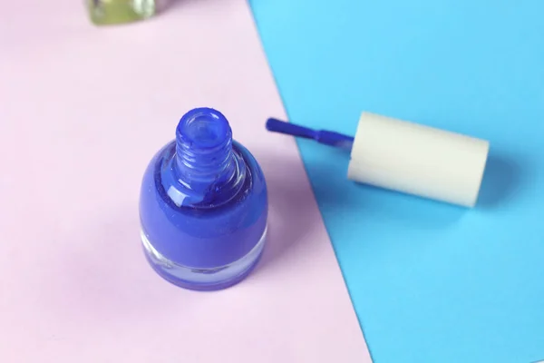 Blue nail lacquer  polish bottle and nail brushes on pink background.  Nail service manicure