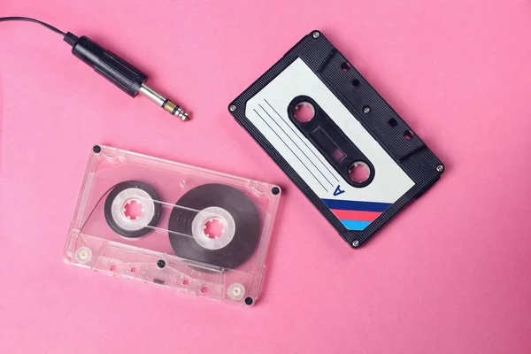 group of two audio retro vintage cassete tape and headphones 80s style on pink background