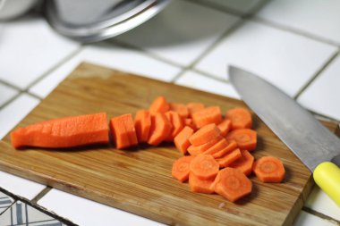 Mutfakta bir bıçakla bir ahşap kesme tahtası üzerinde yemek yemek yemek için havuç dilimlenmiş. Vejeteryan beslenme