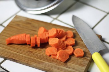 Havuç yemek bir ahşap kesme tahtası üzerinde mutfak bıçağıyla için dilimlenmiş. Vejeteryan beslenme