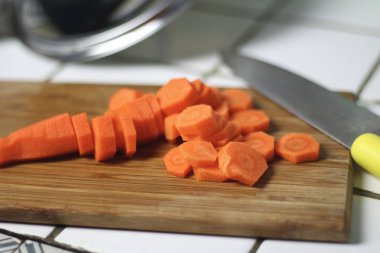 Havuç yemek bir ahşap kesme tahtası üzerinde mutfak bıçağıyla için dilimlenmiş. Vejeteryan beslenme