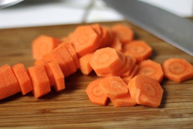 Havuç yemek bir ahşap kesme tahtası üzerinde mutfak bıçağıyla için dilimlenmiş. Vejeteryan beslenme