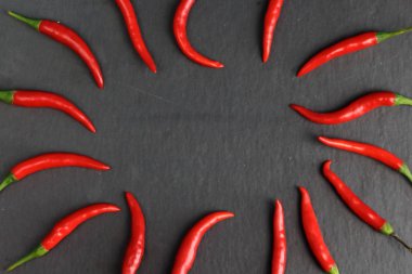Grup keskin sıcak baharat kırmızı biber taze acı biber siyah grafit kayrak taş yüzeyinde güneşin bir daire şeklinde. Doğal vejeteryan diyet organik sebze. Karanlık gıda foto