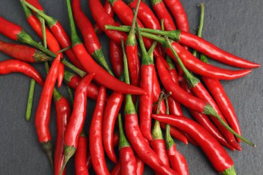 Tazelik su çiğ siyah grafit kayrak taş yüzeyi, keskin sıcak baharat kırmızı biber biber ile ıslak bir sürü bırakır. Doğal vejeteryan diyet organik sebze. Karanlık gıda foto