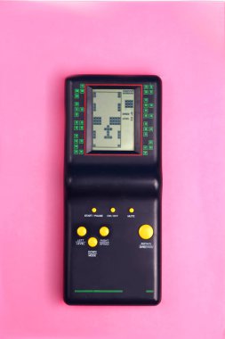 Pembe bir arka plan retro ve grup 80s ve 90s tarzı çocukluk oyundan sarı düğmeleri ile siyah tetris oyun konsolu