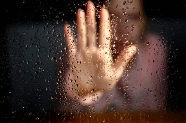 El palm siluet cam ulaşan yağmur damlaları ile pencerenin dışında. Yardım için bir istek, depresyon bokeh arka plan bulanık.