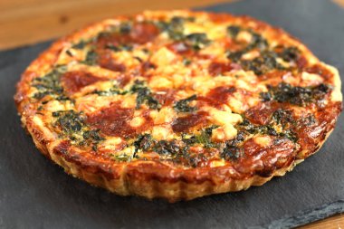 Peynir, ıspanak ve siyah bir tabakta domates İtalyan geleneksel rustik kiş pizza