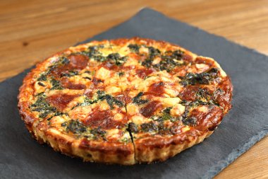 Peynir, ıspanak ve siyah bir tabakta domates İtalyan geleneksel rustik kiş pizza