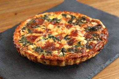 Peynir, ıspanak ve siyah bir tabakta domates İtalyan geleneksel rustik kiş pizza