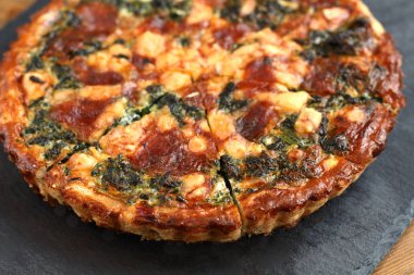 Peynir, ıspanak ve siyah bir tabakta domates İtalyan geleneksel rustik kiş pizza