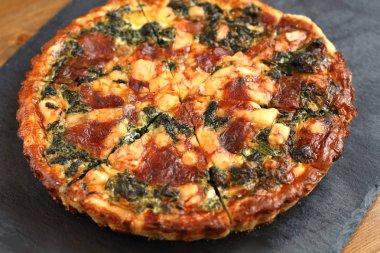 Peynir, ıspanak ve siyah bir tabakta domates İtalyan geleneksel rustik kiş pizza