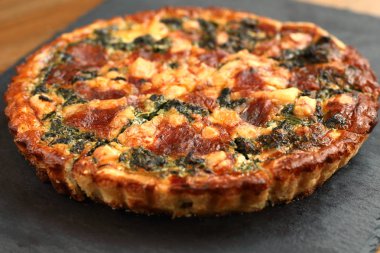 Peynir, ıspanak ve siyah bir tabakta domates İtalyan geleneksel rustik kiş pizza