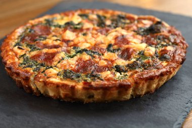 Peynir, ıspanak ve siyah bir tabakta domates İtalyan geleneksel rustik kiş pizza