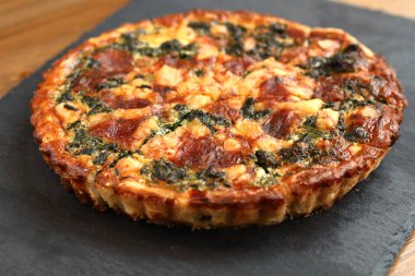 Peynir, ıspanak ve siyah bir tabakta domates İtalyan geleneksel rustik kiş pizza