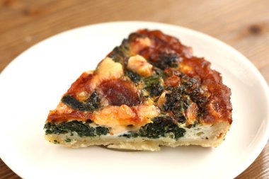 İtalyan geleneksel parça rustik kiş pizza peynir, ıspanak ve restaurante beyaz bir tabakta domates ile