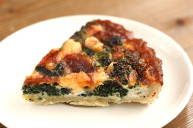 İtalyan geleneksel parça rustik kiş pizza peynir, ıspanak ve restaurante beyaz bir tabakta domates ile