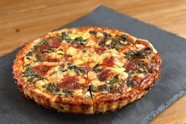 Peynir, ıspanak ve siyah bir tabakta domates İtalyan geleneksel rustik kiş pizza