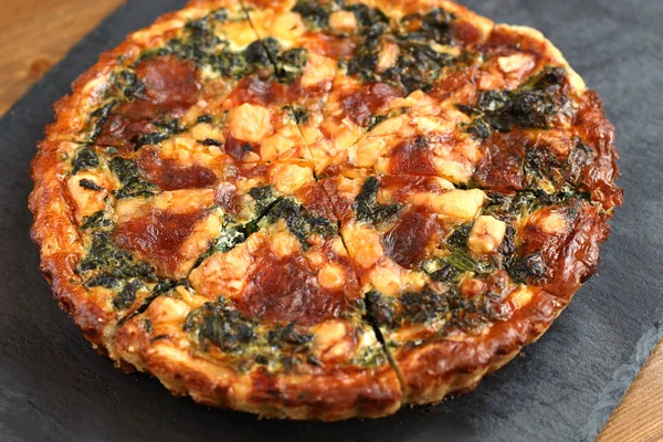 Peynir, ıspanak ve siyah bir tabakta domates İtalyan geleneksel rustik kiş pizza