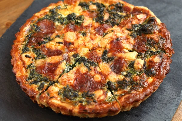 Peynir, ıspanak ve siyah bir tabakta domates İtalyan geleneksel rustik kiş pizza