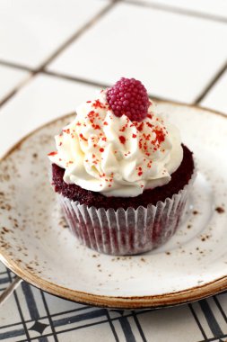 Ev yapımı ekmek stil kırmızı kadife lezzetli sünger kek ile beyaz tereyağı krema buzlanma ve raspberrie üst plaka üzerinde. Şahsın ve doğum günü kutlamak için çikolata