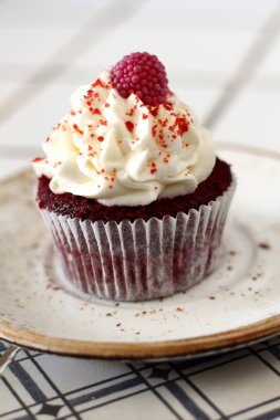 Ev yapımı ekmek stil kırmızı kadife lezzetli sünger kek ile beyaz tereyağı krema buzlanma ve raspberrie üst plaka üzerinde. Şahsın ve doğum günü kutlamak için çikolata