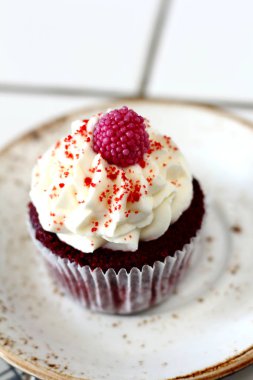 Ev yapımı ekmek stil kırmızı kadife lezzetli sünger kek ile beyaz tereyağı krema buzlanma ve raspberrie üst plaka üzerinde. Şahsın ve doğum günü kutlamak için çikolata