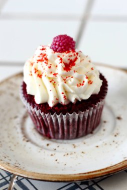 Ev yapımı ekmek stil kırmızı kadife lezzetli sünger kek ile beyaz tereyağı krema buzlanma ve raspberrie üst plaka üzerinde. Şahsın ve doğum günü kutlamak için çikolata