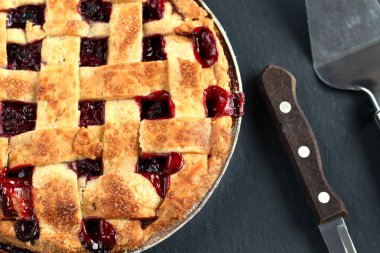 Pasta için kolu ve kepçe ile bıçak ile siyah bir grafit arka planda hamur bir kafes ile geleneksel lezzetli kiraz pastası. Tatil Treat eski moda Retro Amerikan tatlı Pie