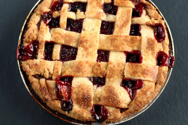 Traditional delicious cherry pie with a lattice of dough on a black graphite background with knife with handle and scoop for cake.Holiday treat old fashioned retro american sweet pie