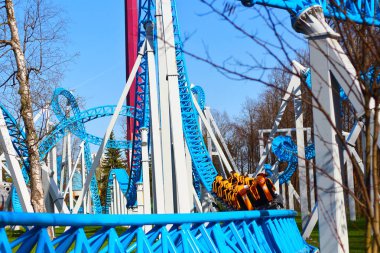 Mavi bir gökyüzüne karşı bir eğlence parkı bir döngü ve bir viraj ile Mavi roller coaster