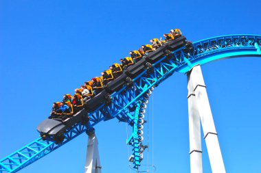 Mavi bir gökyüzüne karşı bir eğlence parkı bir döngü ve bir viraj ile Mavi roller coaster